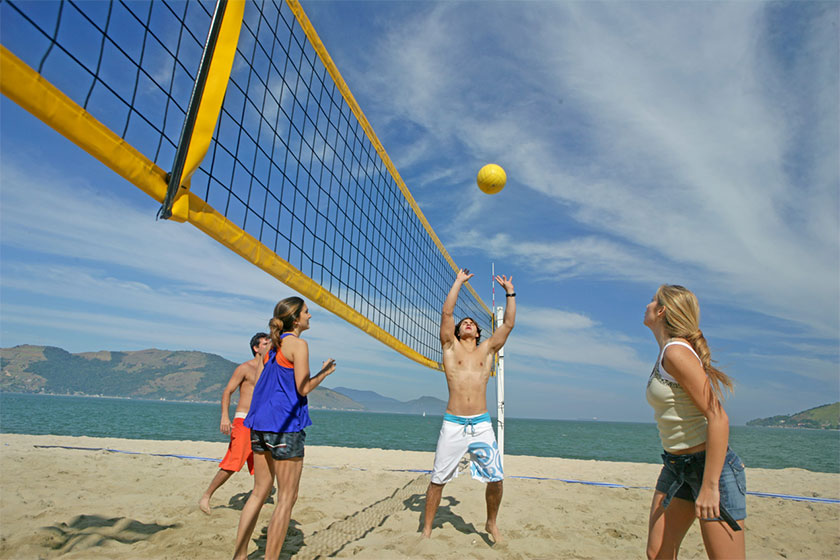 Imagem de pessoas jogando vôlei na praia.