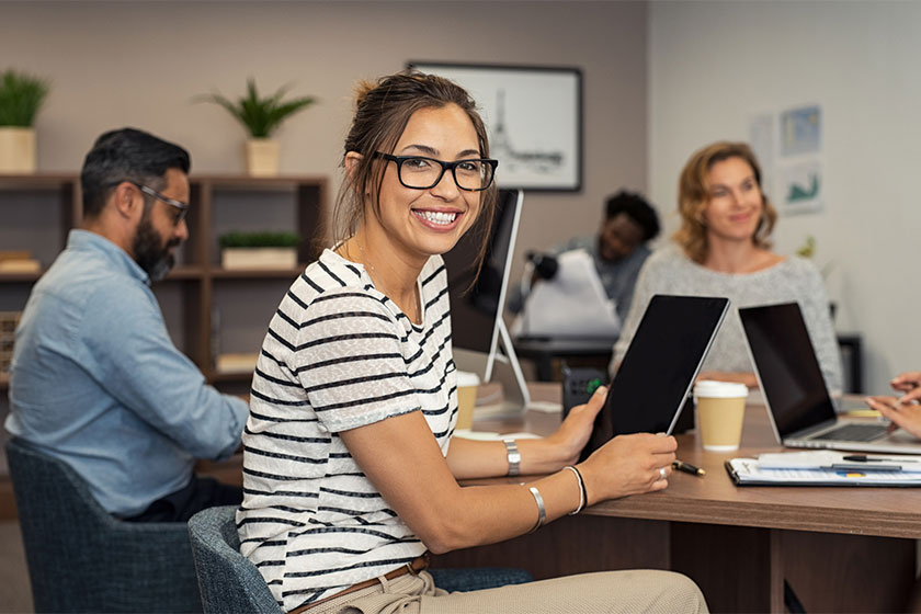 Foto de uma mulher sorrindo no escritório com colegas de trabalho