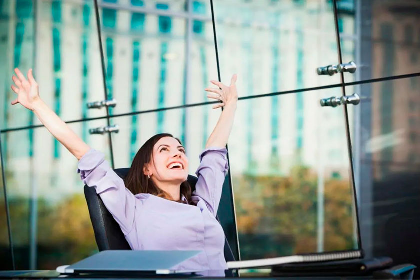 Foto de uma mulher feliz com os braços para cima em seu emprego